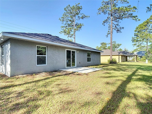 back of property featuring stucco siding, a patio, and a lawn