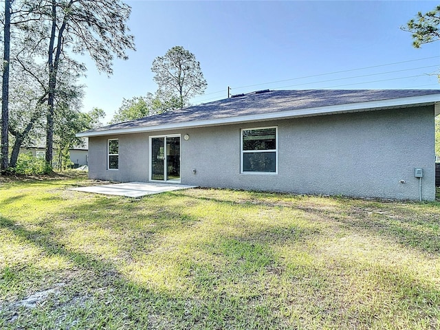 rear view of house featuring stucco siding, a patio area, and a yard