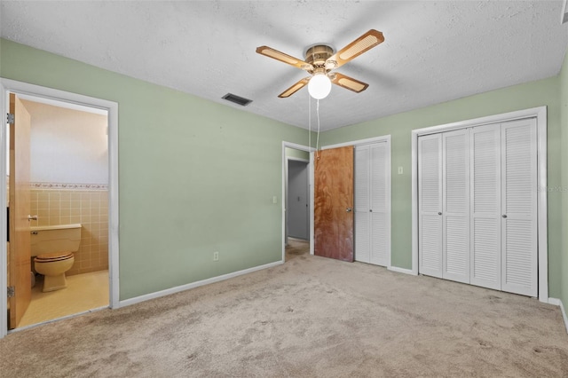 3441 Sherertz Rd, Lakeland, FL 33810 - unfurnished bedroom with multiple closets, ensuite bath, carpet flooring, baseboards, and a textured ceiling