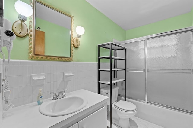 3441 Sherertz Rd, Lakeland, FL 33810 - bathroom featuring tile walls, bath / shower combo with glass door, vanity, toilet, and wainscoting