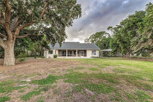 back of property with a sunroom, a yard, and a carport