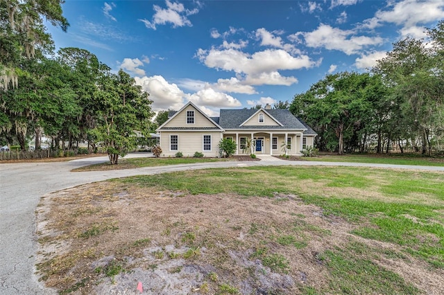 view of front of house with covered porch, fence, curved driveway, and a front yard
