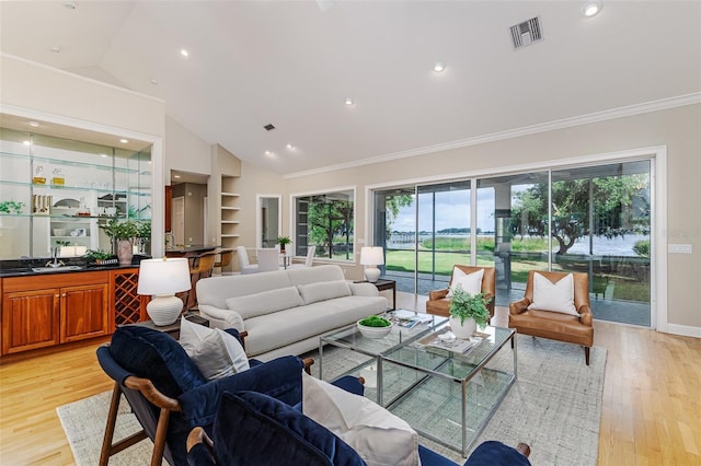 living area with light wood-style floors, high vaulted ceiling, ornamental molding, and visible vents
