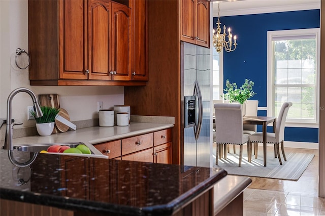 kitchen featuring brown cabinets, a sink, stainless steel fridge with ice dispenser, a notable chandelier, and ornamental molding