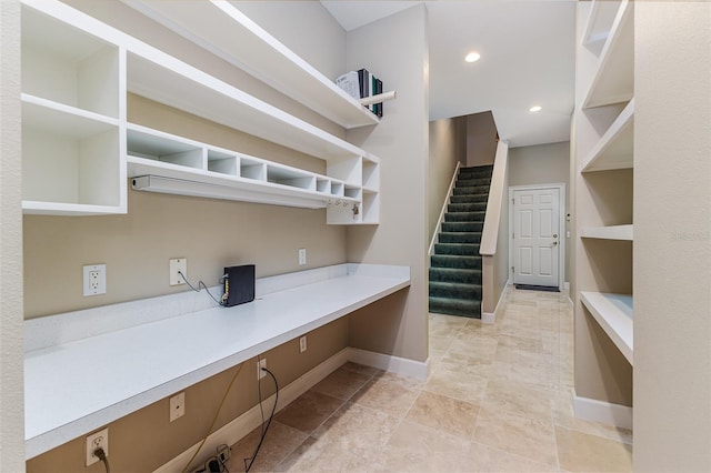 kitchen with light countertops, baseboards, open shelves, and built in desk