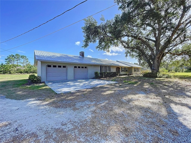 single story home featuring a chimney, a garage, gravel driveway, and metal roof