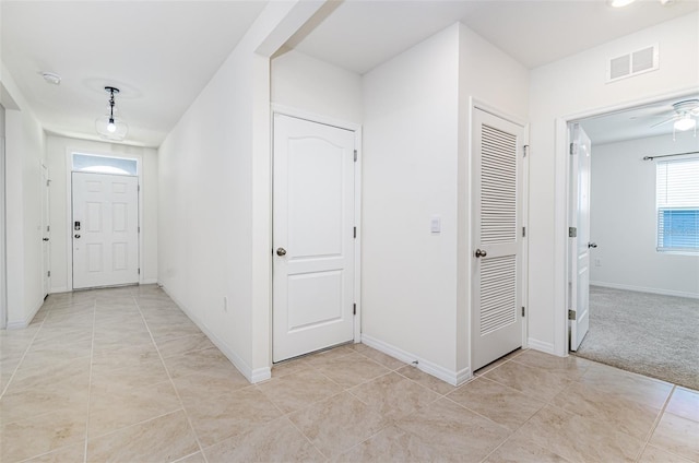 hall featuring visible vents, baseboards, and light tile patterned flooring