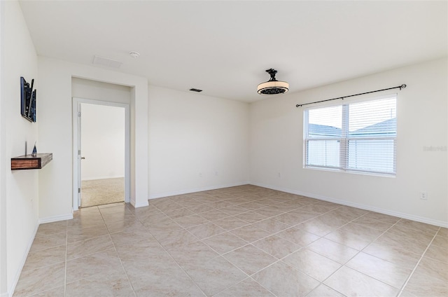 spare room with light tile patterned floors, visible vents, and baseboards