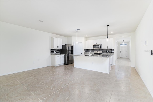 kitchen featuring light tile patterned floors, white cabinets, light stone countertops, appliances with stainless steel finishes, and decorative backsplash