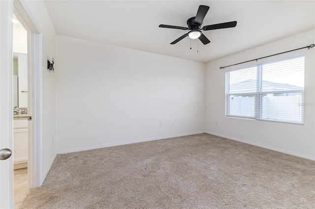 spare room with light carpet, baseboards, and a ceiling fan