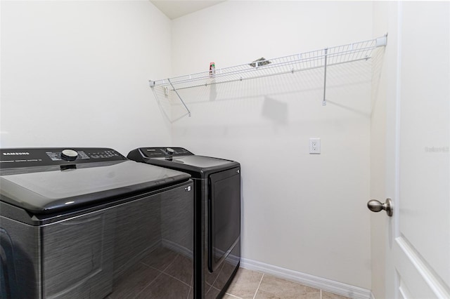 laundry area with washer and clothes dryer, baseboards, and light tile patterned flooring