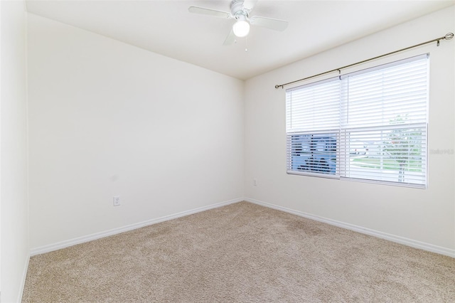 empty room featuring carpet flooring, baseboards, a ceiling fan, and a wealth of natural light
