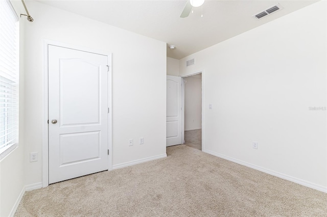 unfurnished bedroom featuring multiple windows, visible vents, and carpet floors