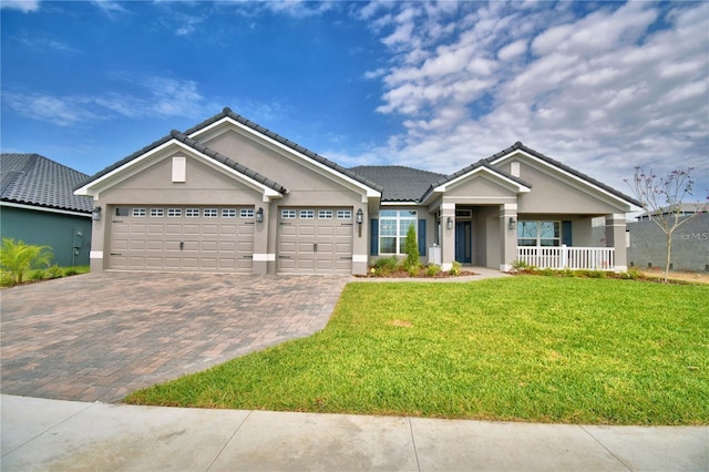 craftsman-style house featuring a tile roof, decorative driveway, a front lawn, an attached garage, and stucco siding