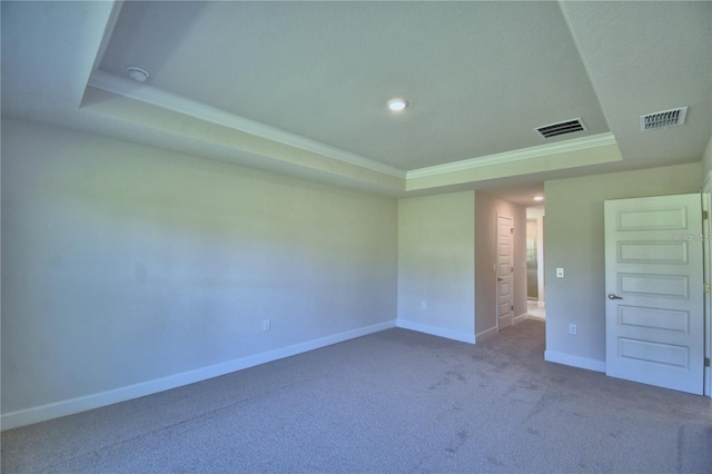 carpeted empty room with visible vents, a raised ceiling, crown molding, and baseboards