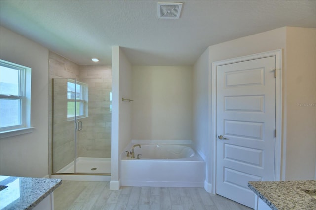 full bathroom with vanity, wood finished floors, visible vents, a bath, and a stall shower