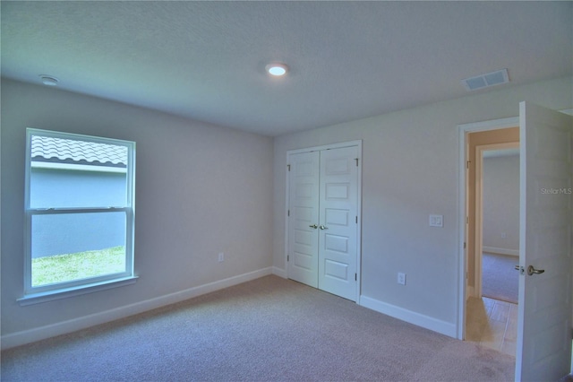 unfurnished bedroom with carpet floors, baseboards, a closet, and visible vents