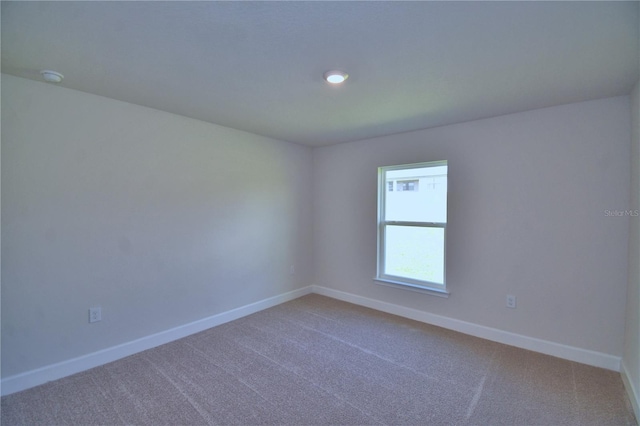 empty room featuring baseboards and carpet