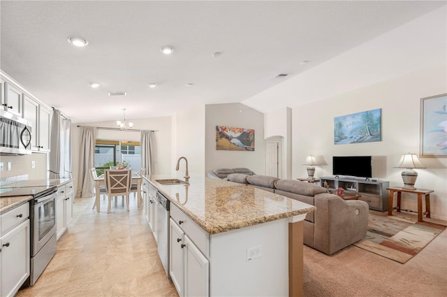 kitchen featuring a kitchen island with sink, vaulted ceiling, a sink, a notable chandelier, and stainless steel appliances
