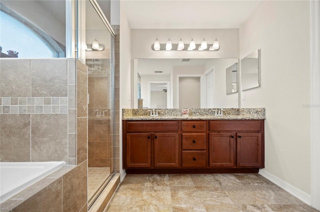 bathroom with double vanity, baseboards, a relaxing tiled tub, a sink, and a stall shower