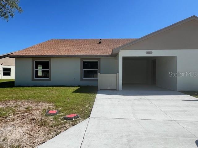 ranch-style house with a front yard, roof with shingles, stucco siding, concrete driveway, and an attached garage