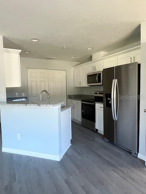 kitchen with a peninsula, appliances with stainless steel finishes, dark wood-style floors, and white cabinetry
