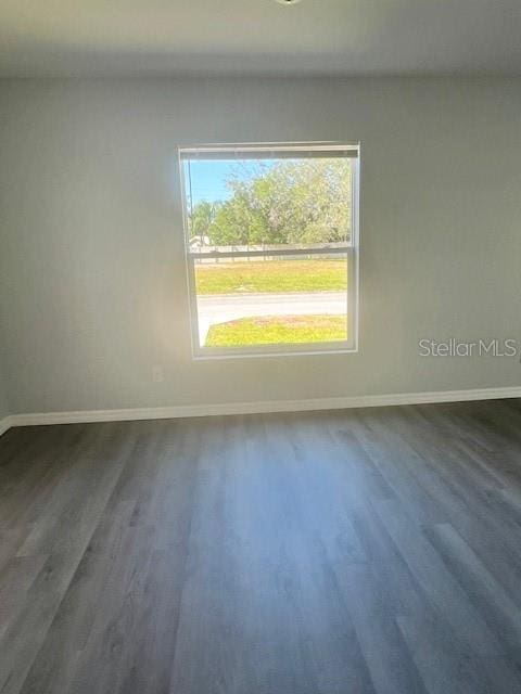 spare room featuring baseboards and dark wood-style floors