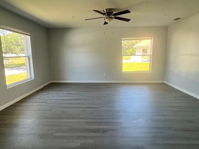 empty room featuring baseboards, a ceiling fan, and dark wood-type flooring