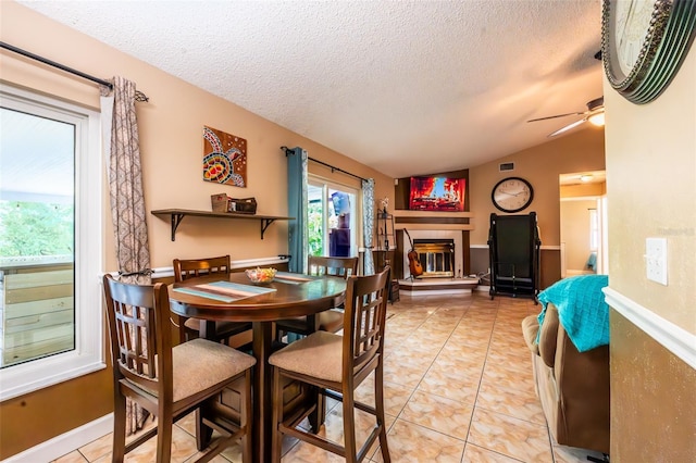 1061 Lowry Ave, Lakeland, FL 33801 - dining room featuring a ceiling fan, a textured ceiling, light tile patterned floors, a tiled fireplace, and vaulted ceiling
