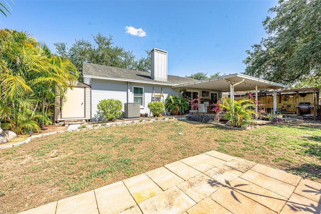 1061 Lowry Ave, Lakeland, FL 33801 - back of property with cooling unit, a patio, a chimney, and a lawn