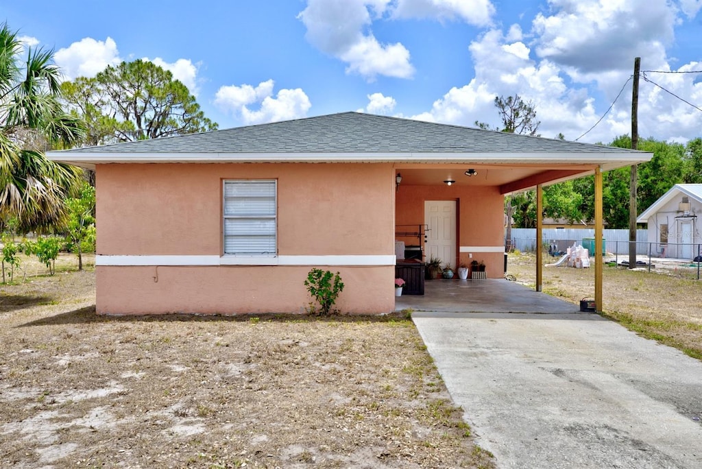 708 Illinois Ave, Wauchula, FL 33873 - view of front of property featuring fence, driveway, stucco siding, an attached carport, and roof with shingles