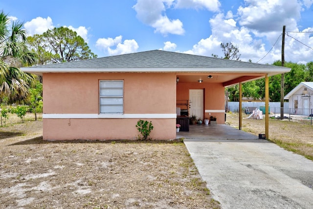 708 Illinois Ave, Wauchula, FL 33873 - view of front of property featuring fence, driveway, stucco siding, an attached carport, and roof with shingles