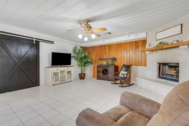 living room featuring a ceiling fan, rail lighting, tile patterned flooring, wood walls, and a fireplace