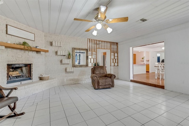 sitting room featuring tile patterned flooring, a brick fireplace, ceiling fan, and visible vents
