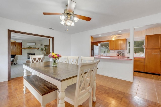 dining area with visible vents, a fireplace, ceiling fan, and light tile patterned flooring