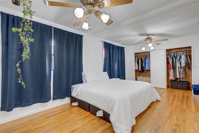 bedroom featuring two closets, wood finished floors, and ceiling fan