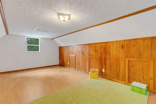 bonus room featuring a textured ceiling, attic access, and wood finished floors