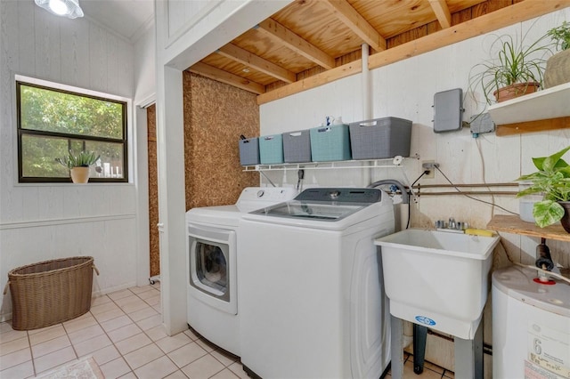 laundry room featuring a sink, wood walls, water heater, light tile patterned floors, and washing machine and dryer