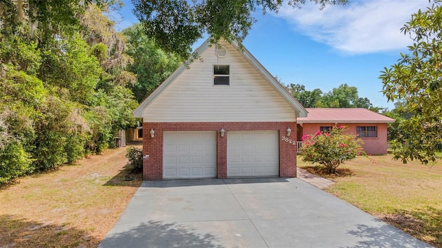 traditional-style house with concrete driveway, brick siding, metal roof, and a front yard
