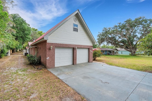view of side of home with concrete driveway, an attached garage, brick siding, and a lawn