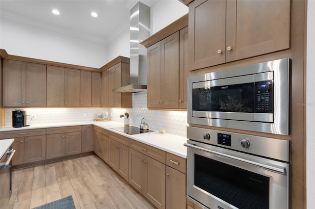 2551 Delphi Woods Cir, Lakeland, FL 33812 - kitchen with stainless steel appliances, wall chimney range hood, ornamental molding, light wood-type flooring, and light countertops