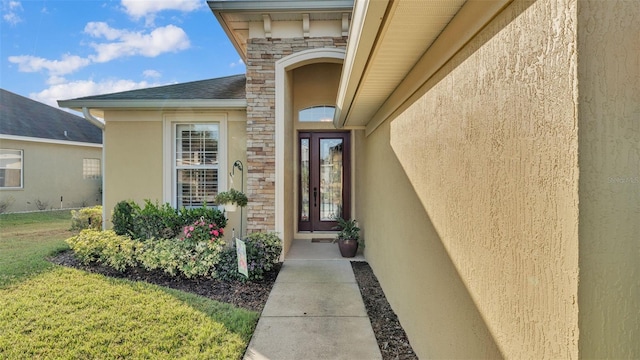 doorway to property featuring stone siding, stucco siding, and a yard
