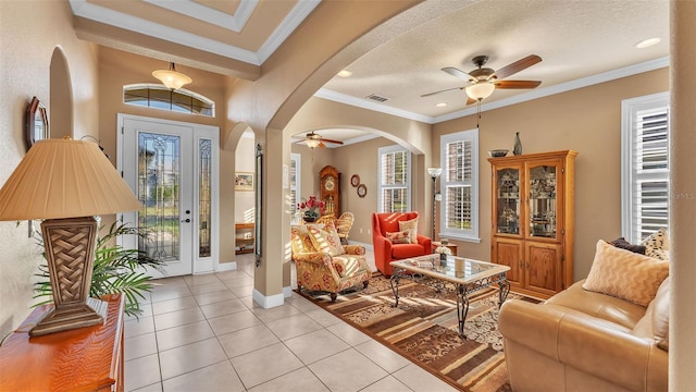 entrance foyer featuring a ceiling fan, arched walkways, light tile patterned floors, crown molding, and baseboards