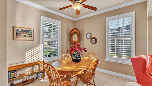 dining area featuring healthy amount of natural light, crown molding, a ceiling fan, light tile patterned flooring, and baseboards