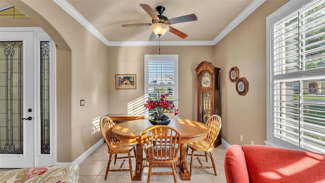dining space featuring light tile patterned floors, arched walkways, a ceiling fan, baseboards, and crown molding