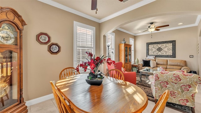 dining space with a ceiling fan, arched walkways, light tile patterned floors, ornamental molding, and baseboards