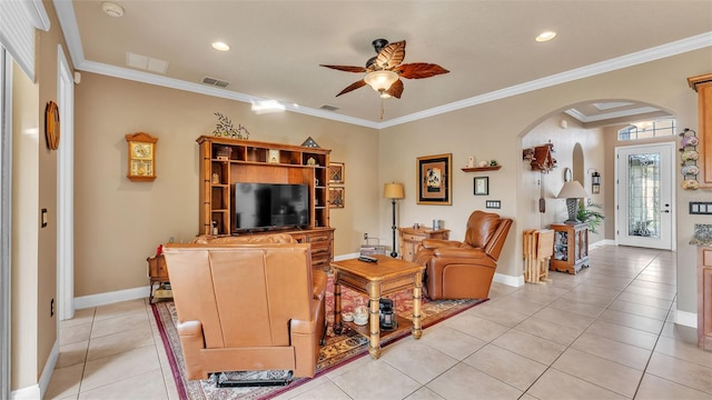 living area featuring arched walkways, ceiling fan, light tile patterned floors, baseboards, and crown molding