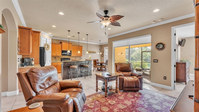 living area with light tile patterned floors, a ceiling fan, recessed lighting, a textured ceiling, and crown molding