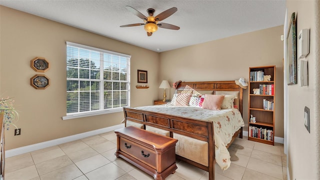 bedroom with baseboards, light tile patterned flooring, ceiling fan, and a textured ceiling