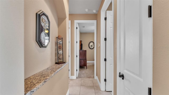 corridor with light tile patterned floors and baseboards